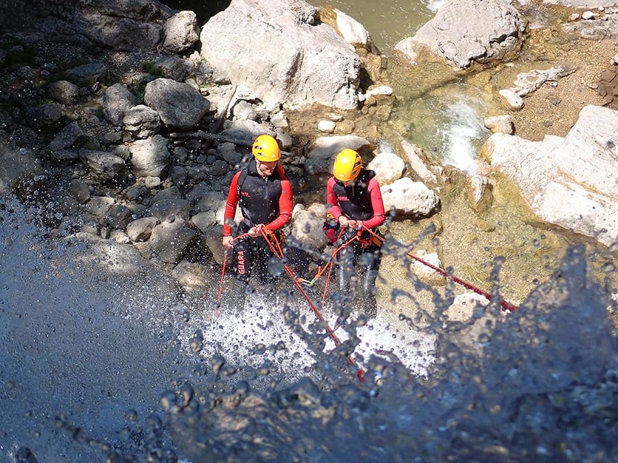 Deux aventuriers enthousiastes descendent en rappel dans une cascade lors d'une expérience de canyoning à Lyon