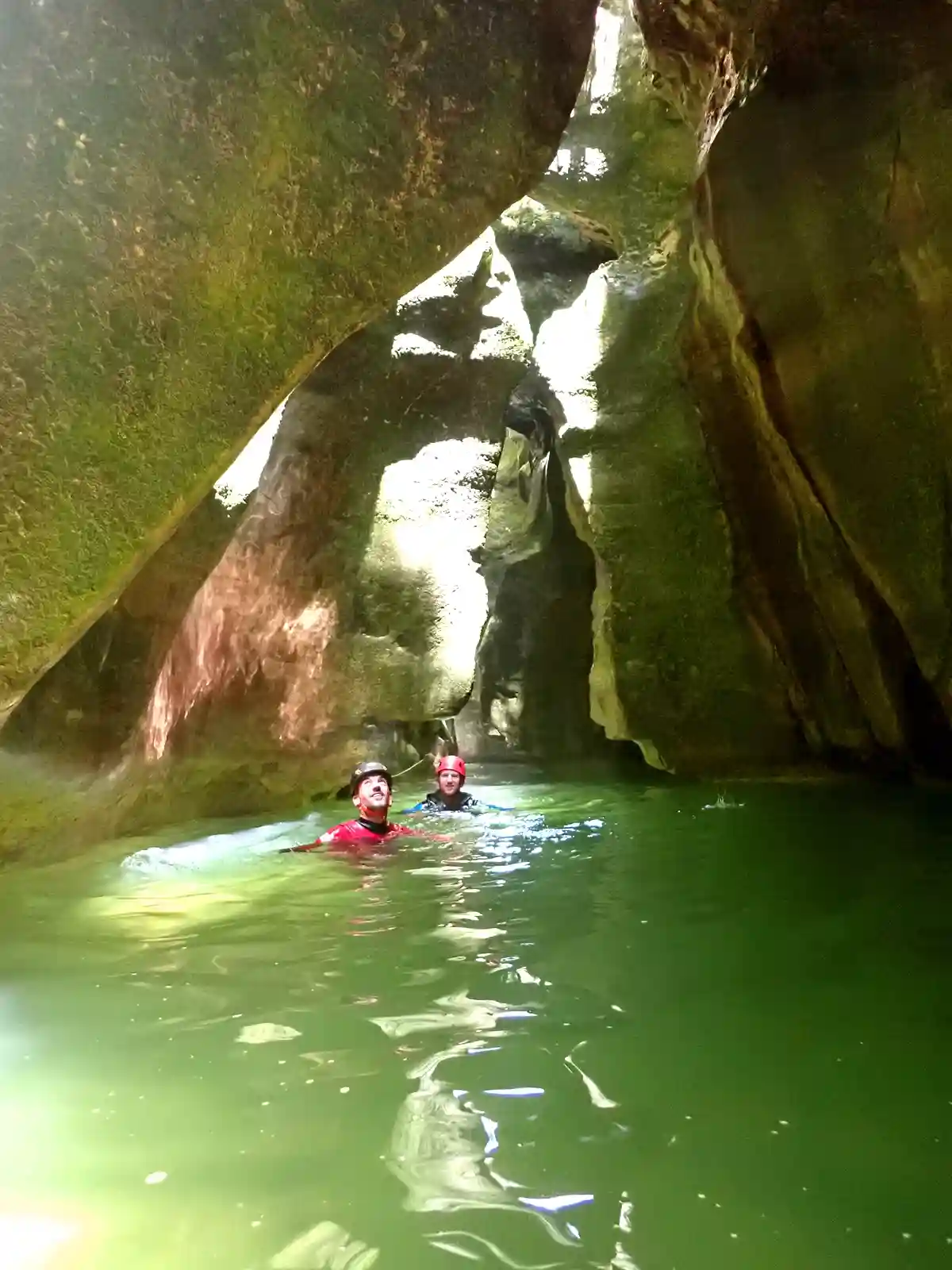 Nage dans une vasque aux eaux turquoise sous une arche rocheuse dans le canyon du Groin, canyoning dans l'Ain